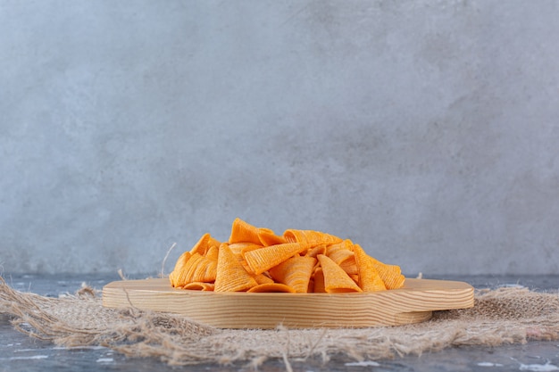 Chip di cono di patate in piatto di legno su struttura, sulla superficie di marmo