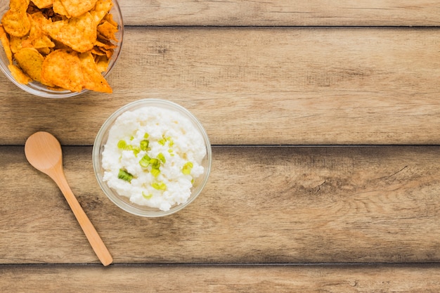 Chip di nachos con ciotola di tuffo di formaggio e cucchiaio di legno sul tavolo