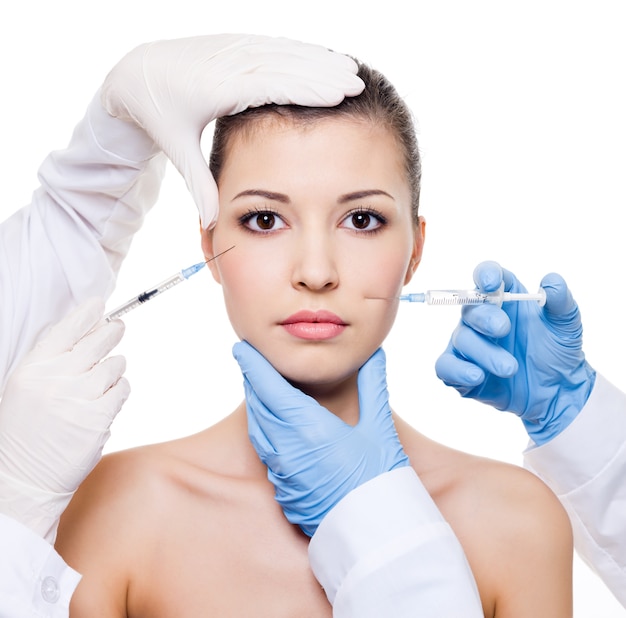 Chirurghi plastici che danno iniezione di botox nella pelle femminile di occhi e labbra isolato bianco