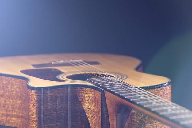 Chitarra acustica con un bellissimo legno su sfondo nero alla luce di un riflettore.