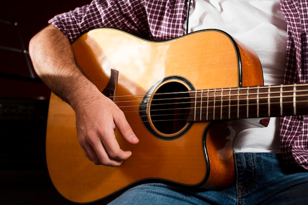 Chitarra acustica del primo piano e seduta del tipo