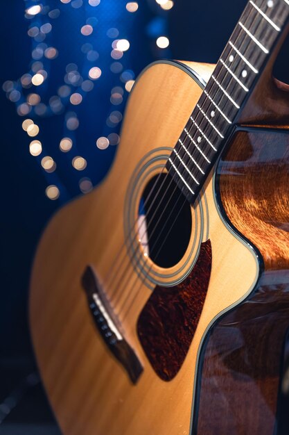 Chitarra acustica del primo piano su uno sfondo scuro con luci bokeh