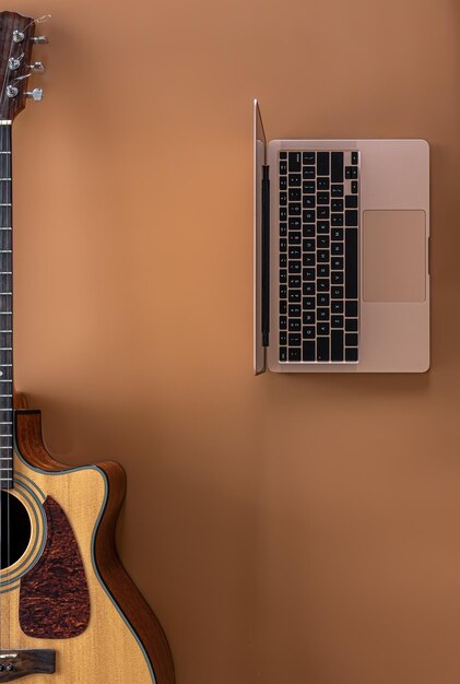 Chitarra acustica e laptop su uno spazio di copia vista dall'alto sfondo marrone