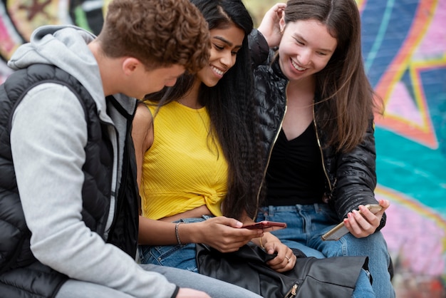 Chiuda in su adolescenti sorridenti con i telefoni