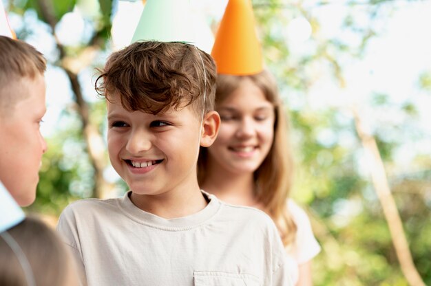 Chiuda in su bambini sorridenti con cappelli da festa
