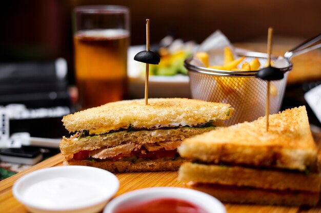 Chiuda in su del panino del randello del pollo con i sottaceti della maionese della lattuga del cetriolo del pomodoro serviti con le fritture