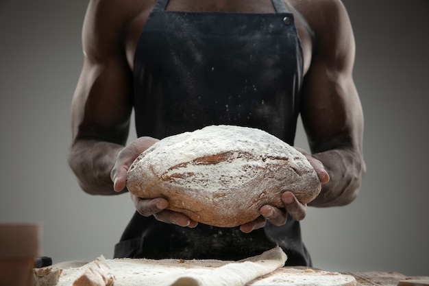 Chiuda in su dell'uomo afro-americano cuochi cereali freschi, pane, crusca sulla tavola di legno. Mangiare gustoso, nutrizione, prodotto artigianale. Cibo senza glutine, stile di vita sano, produzione biologica e sicura. Fatto a mano.