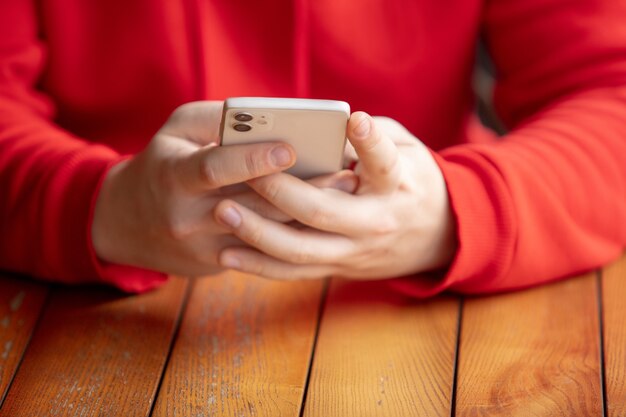 Chiuda in su dell'uomo che utilizza telefono astuto mobile isolato sul muro bianco. Stile di vita, concetto di moderne tecnologie.