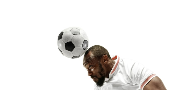 Chiuda in su dell'uomo emotivo che gioca a calcio che colpisce la palla con la testa sul muro bianco isolato
