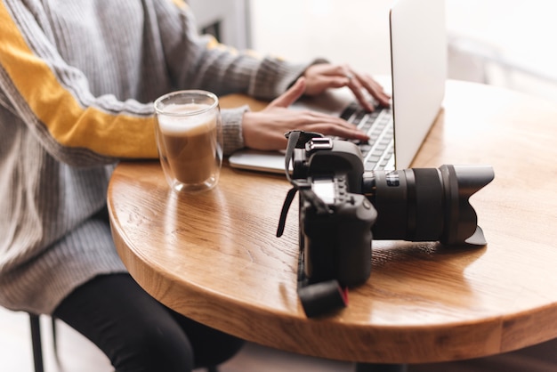 Chiuda in su della donna che digita sul computer portatile nella caffetteria