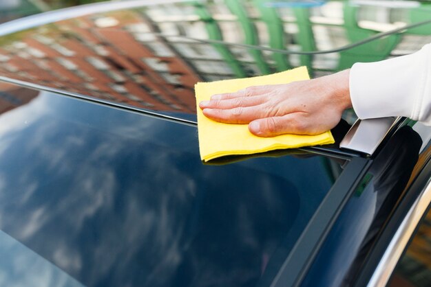 Chiuda in su della persona che pulisce l&#39;esterno dell&#39;automobile