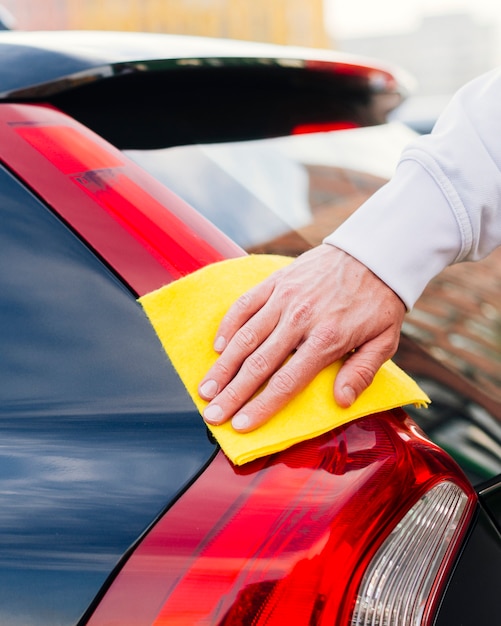 Chiuda in su della persona che pulisce l&#39;esterno dell&#39;automobile