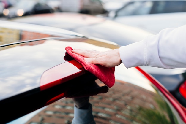 Chiuda in su della persona che pulisce l&#39;esterno dell&#39;automobile