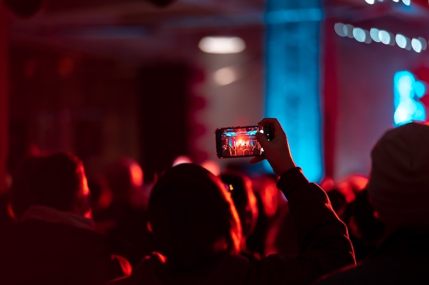 Chiuda in su della registrazione di video con lo smartphone durante un concerto. Immagine tonica