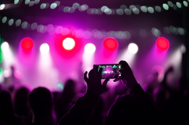 Chiuda in su della registrazione di video con lo smartphone durante un concerto