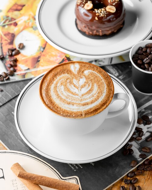 Chiuda in su della tazza del caffè del cappuccino e della torta di cioccolato