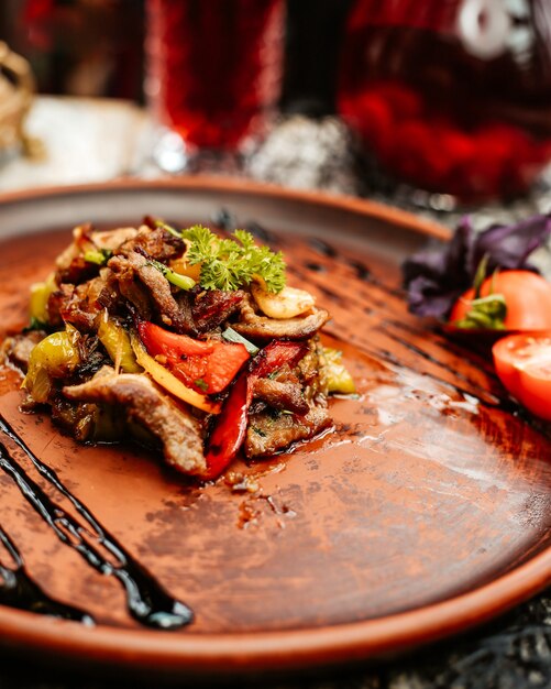 Chiuda in su delle fette fritte dell'agnello con i peperoni dolci e le erbe verdi e rossi gialli