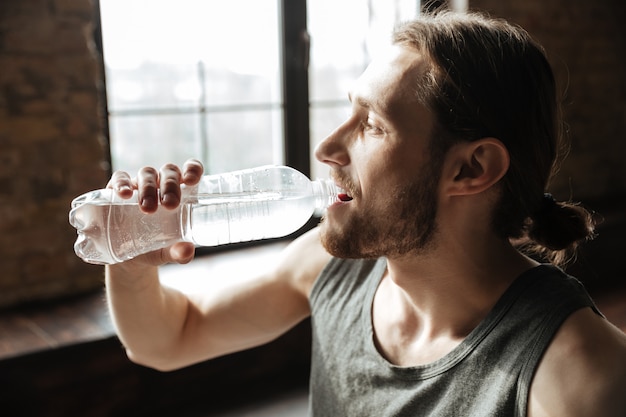 Chiuda in su di un'acqua potabile sana del giovane uomo di forma fisica