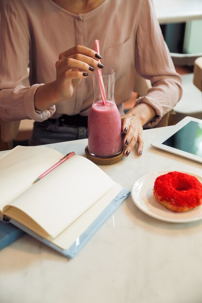 Chiuda in su di una ragazza che mangia un cocktail del frullato