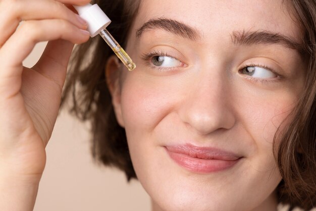 Chiuda in su ragazza sorridente con siero per il viso