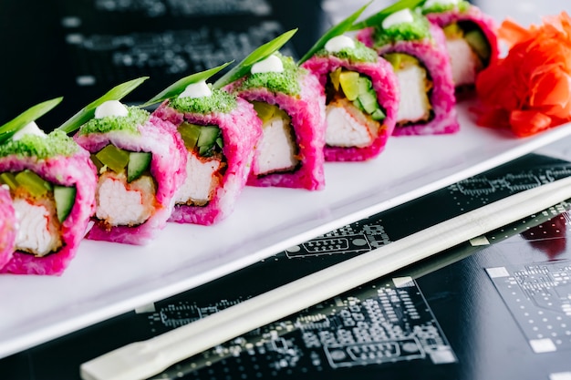 Chiuda su dei rotoli di sushi porpora con i bastoncini di granchio fritti cetriolo e peperone dolce