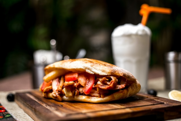 Chiuda su del doner di pollo con le patate fritte del pomodoro servite con l'ayran