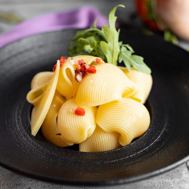 Chiuda su della pasta della conchiglie della conchiglie guarnita con l'insalata del cubo della cipolla e del pomodoro