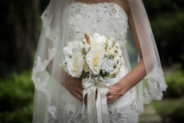 Chiuda su della sposa con il fiore nuziale di nozze in mani.