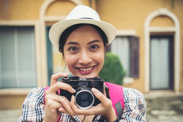 Chiuda su dello zaino della donna dei giovani pantaloni a vita bassa che prende la foto in urbano.