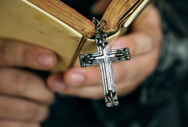 Chiuda su di un uomo che legge una bibbia con la religione d'attaccatura e il concetto di credenza trasversali