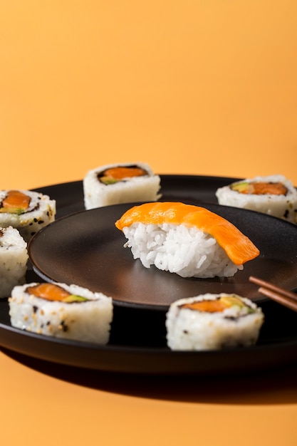 Chiuda sui rotoli di sushi di maki con il nigiri su fondo giallo