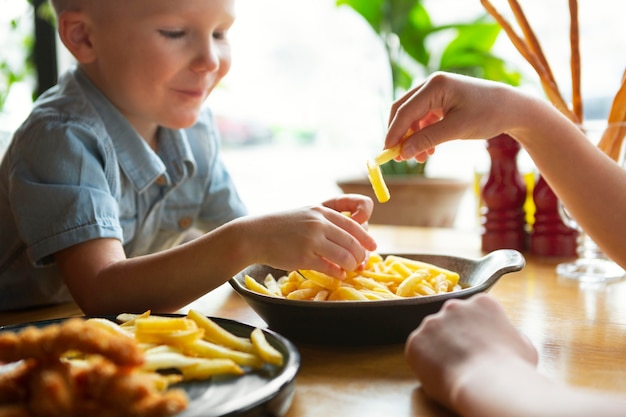 Chiuda sul bambino che mangia patatine fritte