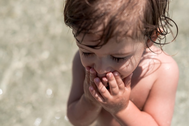 Chiuda sul bambino con gli occhi chiusi giocando in acqua