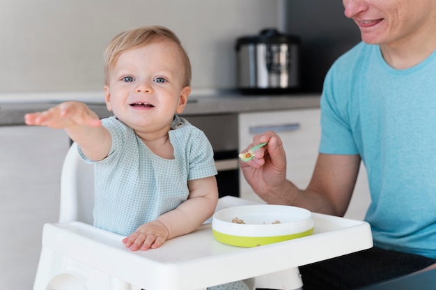 Chiuda sul bambino di alimentazione del padre