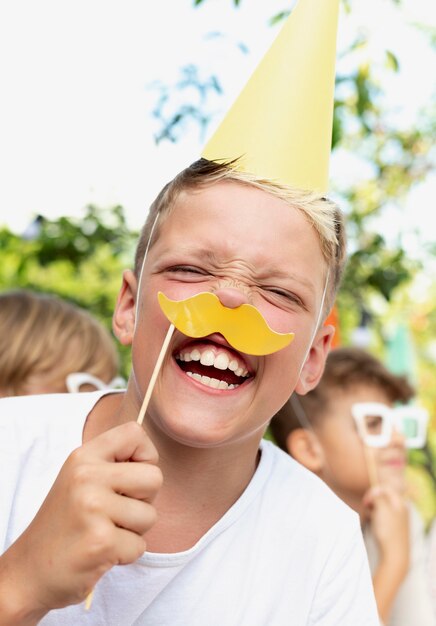 Chiuda sul bambino sorridente che tiene i baffi