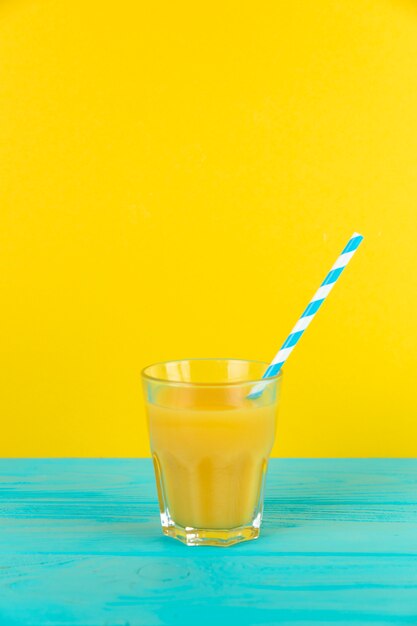 Chiuda sul colpo del vetro fresco del succo d&#39;arancia con fondo giallo