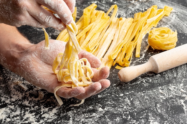 Chiuda sul cuoco unico che produce la pasta vicino al matterello