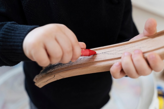 Chiuda sul disegno del bambino sul pezzo di legno