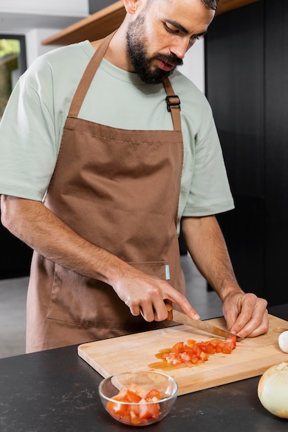 Chiuda sul pomodoro di taglio dell'uomo