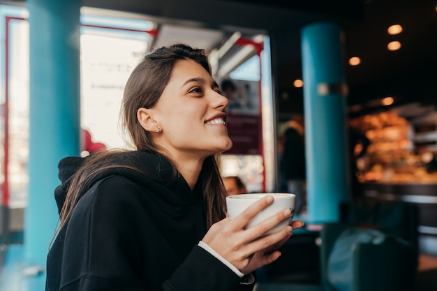 Chiuda sul ritratto del caffè bevente femminile grazioso.