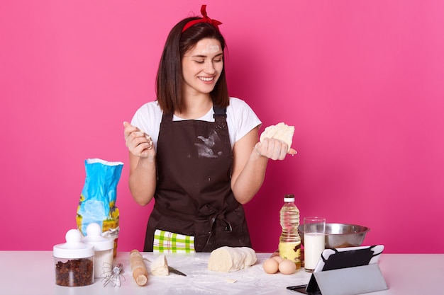 Chiuda sul ritratto del panettiere in grembiule che prepara il forno farcito delle torte, casalinga che prepara per Pasqua