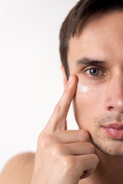 Chiuda sul ritratto dell&#39;uomo che applica la crema per il viso