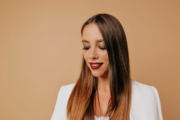 Chiuda sul ritratto della donna di bella donna elegante con trucco luminoso che posa alla macchina fotografica