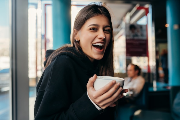 Chiuda sul ritratto della donna graziosa che beve caffè.