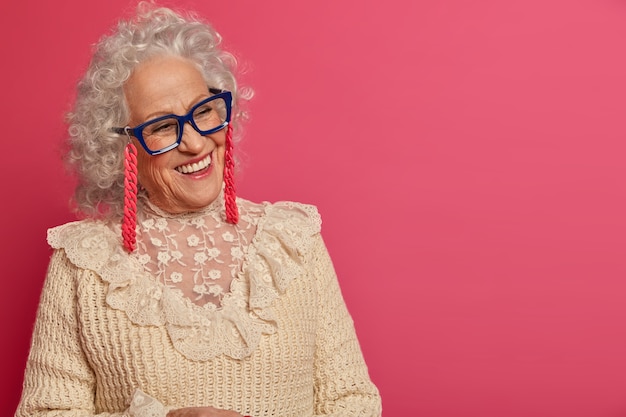 Chiuda sul ritratto della nonna alla moda rugosa felice con gli occhiali e il maglione