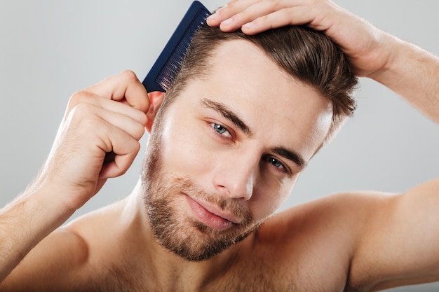 Chiuda sul ritratto di un uomo sorridente che pettina i suoi capelli