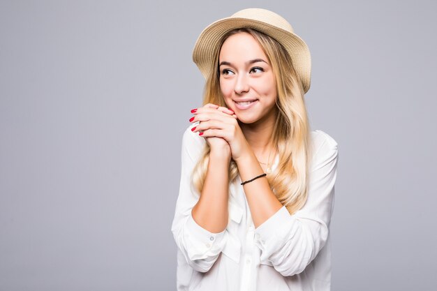 Chiuda sul ritratto di una giovane donna sorridente in cappello che guarda lontano lo spazio della copia isolato sopra il muro grigio