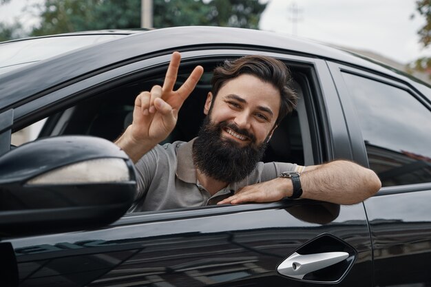 Chiuda sul ritratto laterale dell'uomo felice che conduce l'automobile