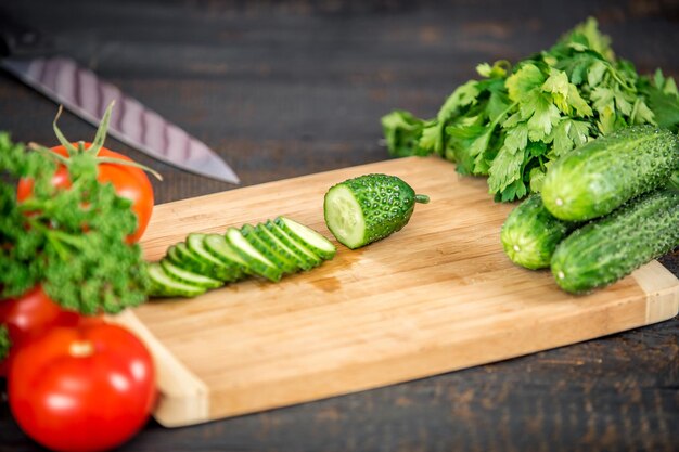 Chiuda sul taglio del cetriolo, facendo l'insalata. Capo taglio verdure. Stile di vita sano, cibo dietetico