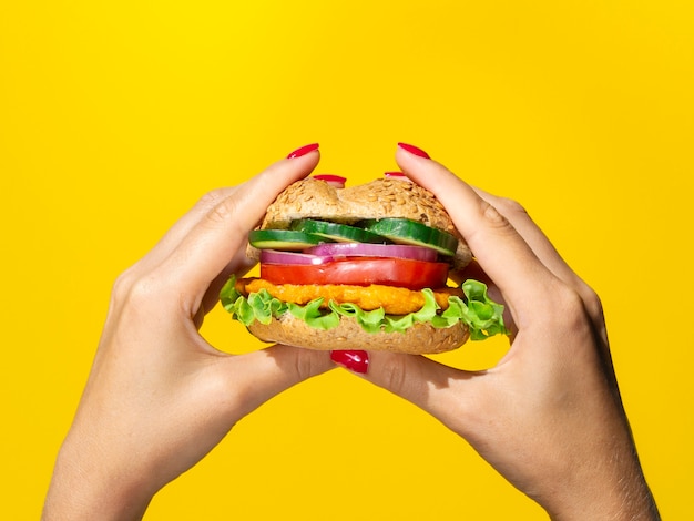Chiuda sull'hamburger saporito di vista su fondo giallo